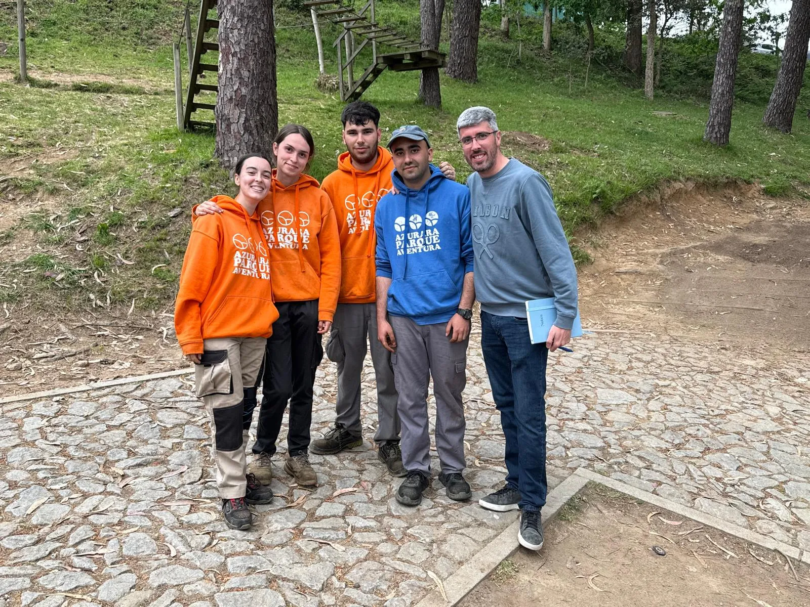 Students wearing adventure park hoodies with their teacher in a forest