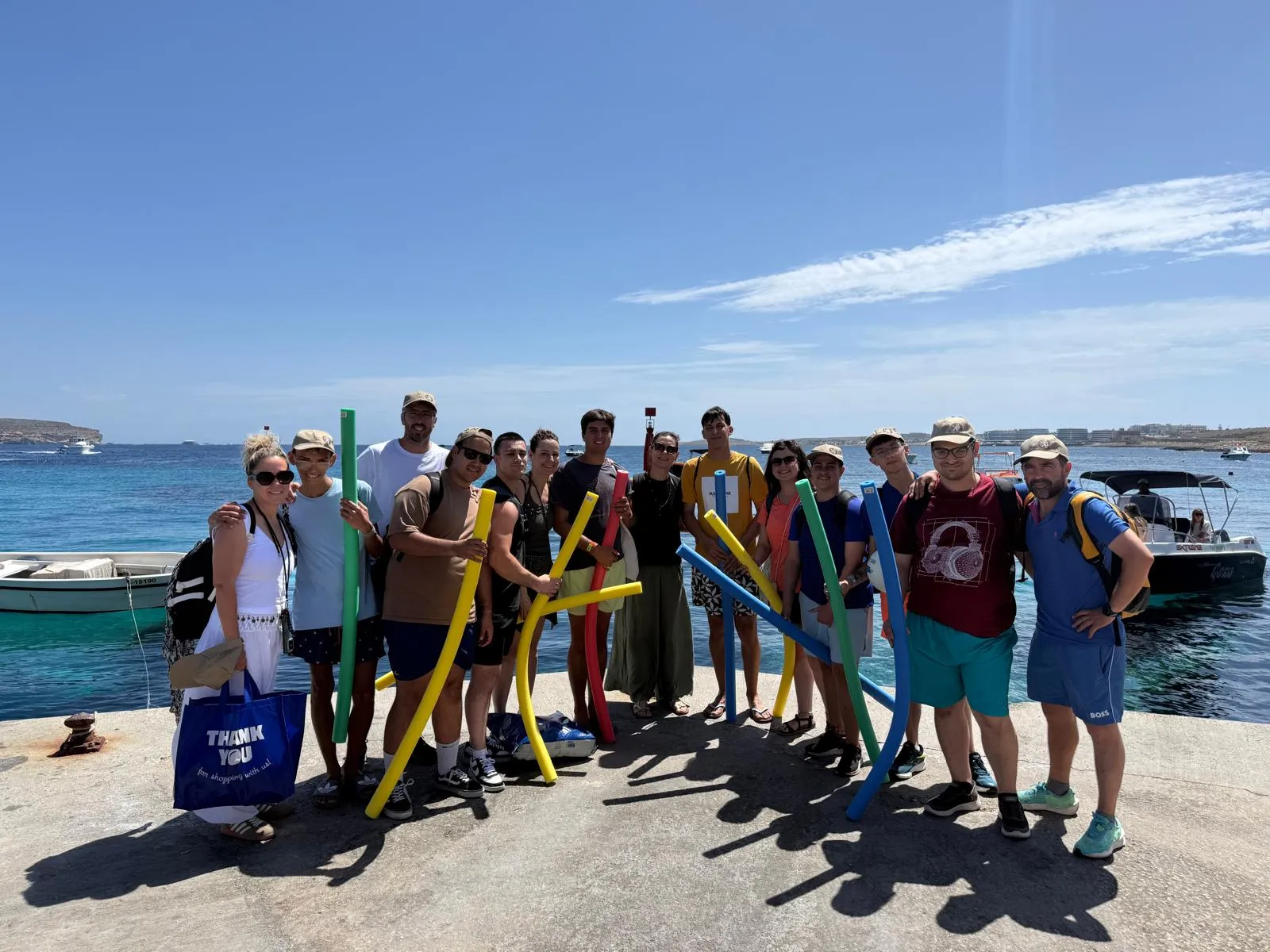 Students and teachers holding pool noodles on a pier by the sea